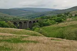 A stone viaduct at the head of a valley with steep sided hills all around