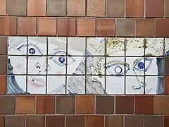 Tiles with blue abstract portraits on a brown tile wall