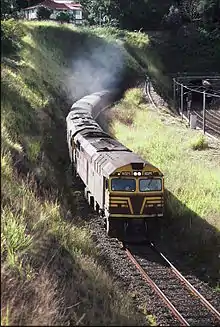 NSWR loco 8025 and another haul the Sydney bound 'Brisbane Limited' past the former Gloucester Road station site, 1987