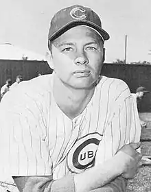 A man in a white baseball uniform with dark pinstripes and a dark cap