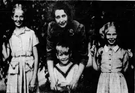 A woman poses with three smiling children.