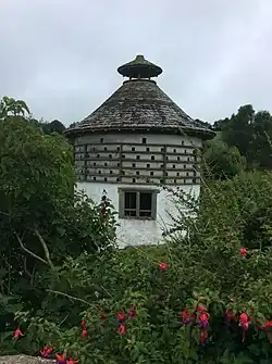 A stone circular building with a conical roof and lantern cap at the top