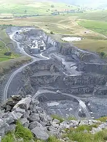 A deep quarry sunk below the surrounding ground, with upland marshes and fields beyond