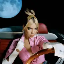 Dua Lipa driving a car in a cosmos. On the top left, there is a moon.