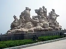 The statue of eight Immortals of Chinese myth in Penglai, Shandong. Lan Caihe is in the middle, holding a large bouquet of roses. nd.