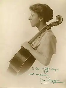 A white woman in profile, with a cello; the photograph is autographed in blue ink