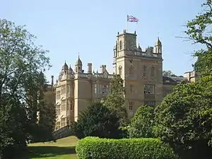 A mansion surrounded by trees and hedges.