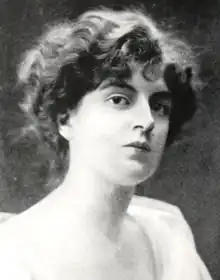 A young white woman with dark wavy hair, dressed back to the nape