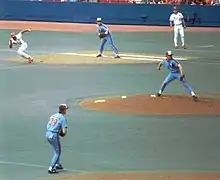 A St. Louis runner breaks from first base as the Expos pitcher throws to the plate.