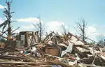 Here, the roof and all but some inner walls of this frame home have been demolished. While taking shelter in a basement, cellar, or inner room improves one's odds of surviving a tornado drastically, occasionally even this is not enough.