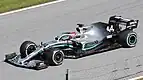 A black Formula One car drives between some gravel and some tarmac on a paved area painted in the colours of the Italian flag.