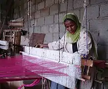 An Ethiopian woman, a member of FWFCA, working at a loom