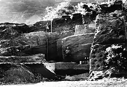 Photograph of two men standing at different levels on an excavated hillside