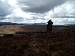 A stone cairn with mountains and hills beyond