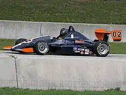 a small open wheeled race car with large aerodynamic wings