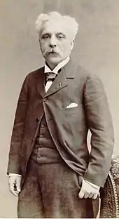 a middle-aged man in 19th century dress looking at the camera; he has greying hair and a large moustache