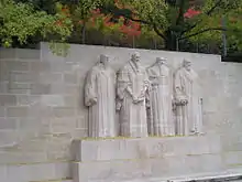 A stone wall with the sculptures of four bearded men