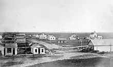 Black-and-white photo: ca. 20 one-story buildings on treeless prairie