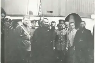 A grainy  black and white photograph of a dozen men, most wearing military uniforms