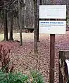 Signpost at the Kucja Valley Mass Grave (defaced with "Rest in peace" obliterated)