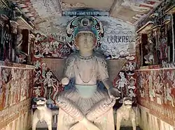 Figure of Maitreya Buddha in cave 275 from Northern Liang (397–439), one of the earliest caves. The crossed ankle figure with a three-disk crown shows influence from Kushan art. Mogao Caves