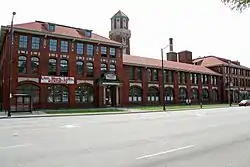 Image of a block long brick building with a tower behind it