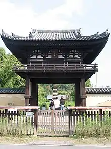 Small, high wooden gate with a railed veranda on the upper floor and a hip-and-gable roof.