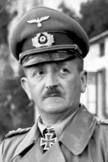 Male in German uniform with peaked cap and toothbrush moustache