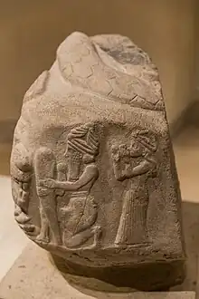 A God putting a foundation nail in the ground, protected by a Lama goddess, in front of a roaring lion. Coiled snake on top. Inscriptions in Linear Elamite and Akkadian. Time of Puzur-Inshushinak, circa 2100 BC, Louvre Museum.