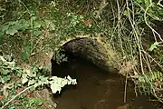 A small stream emerges from a brick culvert.