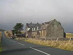 A short terrace of stone houses by a tarmacked road. The area is an upland setting.