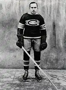 The ice hockey player stands, looking younger but wearing similar equipment and uniform.