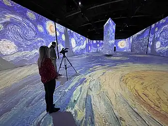 two people photograph an immersive exhibit with a van gogh theme