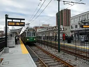 A light rail train at a surface station in the median of an urban street