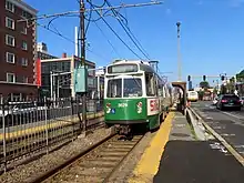 A light rail train at a surface station in the median of an urban street