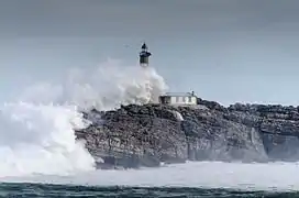 Waves crash over the lighthouse