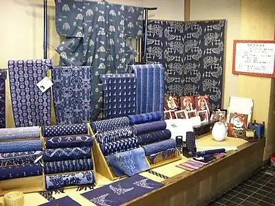 Tanmono, traditional narrow Japanese fabric bolts. This is cotton dyed with indigo before weaving (kasuri) Behind is a yukata (type of kimono) made from this cloth.