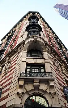 Detail of the chamfered corner on the facade of the Seville Hotel (now James New York NoMad). The chamfered corner connects the Madison Avenue and 29th Street facades at a 45-degree angle. It contains balconies, limestone ornaments, and a curved metal window bay.