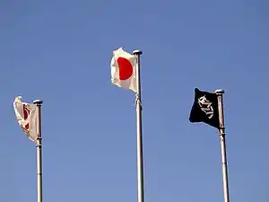 Three flags fly in the sky.