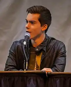 The image is of a young man talking into a microphone