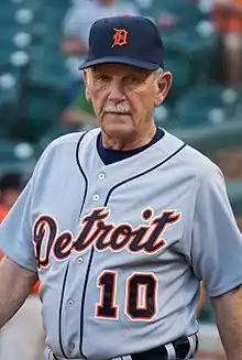 A man in a gray baseball uniform and navy blue cap