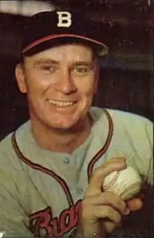 A man in a gray baseball uniform and navy blue cap