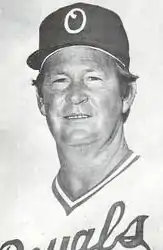 A man in a light baseball jersey and dark cap