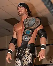 Johnny Impact with the fifth design of the belt, introduced in 2018, in its blue version.