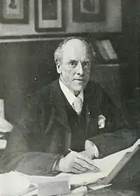 Man seated at his desk looking up at the camera