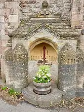 Colour photograph of the drinking fountain, with cast iron tap and water pump fittings painted in red, built into a niche on the east side of the tower.