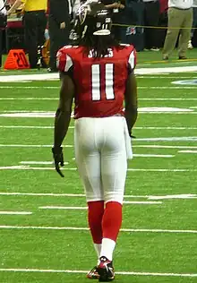 An American football player carrying the ball in a blue #24 jersey with white pants and helmet evades a tackle.