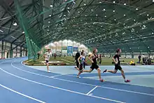 Indoor track and field facility with a group of runners circling the track