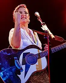 A photograph of Tunstall smiling, looking away from the camera. A microphone is positioned in front of her face.