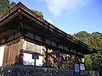 Wooden building on a stone platform with white walls.